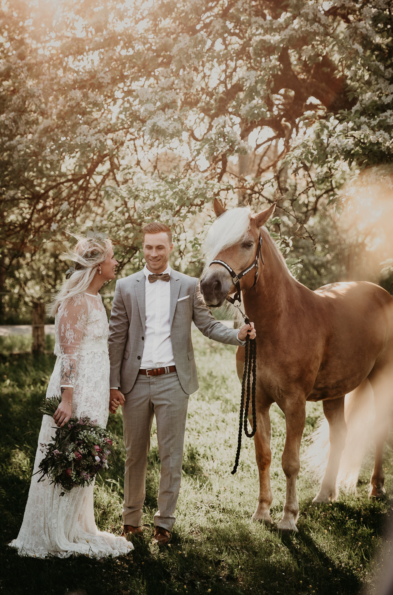 Bröllopsfotograf_Skåne_med hästar_av_Fotoepok-80 Brudpar i den skånska naturen med brudbukett i handen och underbart solnedgång och med sin häst